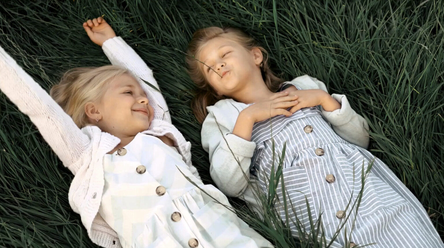 Billedet viser to piger som hygger i græsset