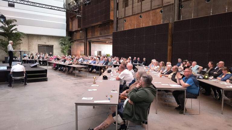 Billedet viser bestyrelsesmøde hvor formanden taler på scenen
