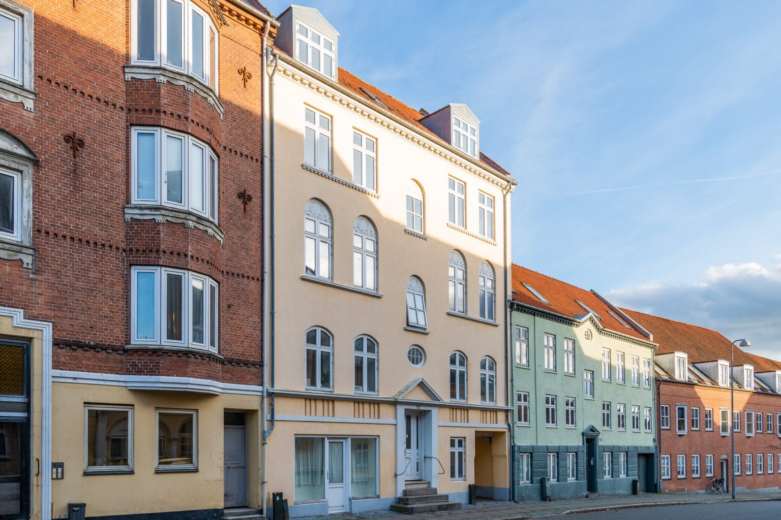 Billedet viser en gul bygning i Smedegade